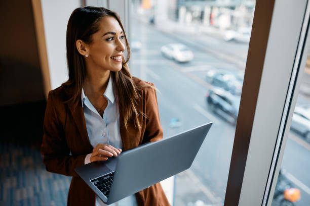 istock Happy female entrepreneur using laptop and looking through the window in the office. 1447567264