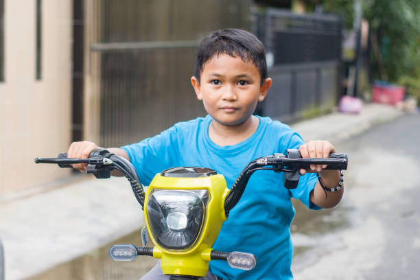 Father and son ride scooter through countryside on sunny summer afternoon. Spending time together.