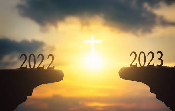 New hope concept: 2023 on sunset sky background with white cross stock photo