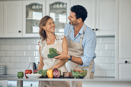 Couple, cooking and vegetable in kitchen together, healthy food and nutrition, happy with chef skill at home. Man, woman and cook with smile, fresh organic vegetables and preparing salad for meal.
