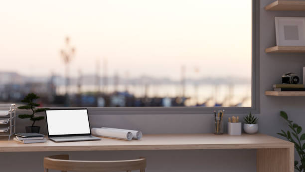 istock Architect and engineer office desk with laptop, blueprints and office supplies on table against window 1447578230