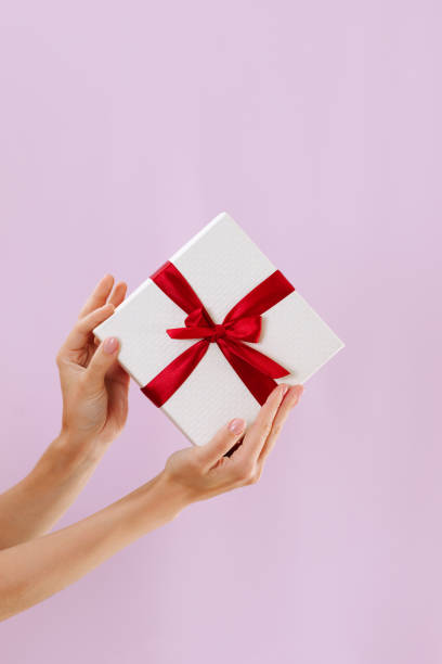 istock Women's hands hold a white with a red ribbon bow 1447581569