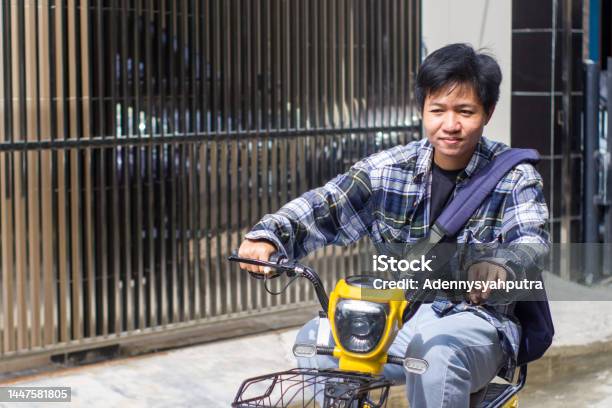 Young Men Riding Electric Bikes In Residential Area Stock Photo - Download Image Now