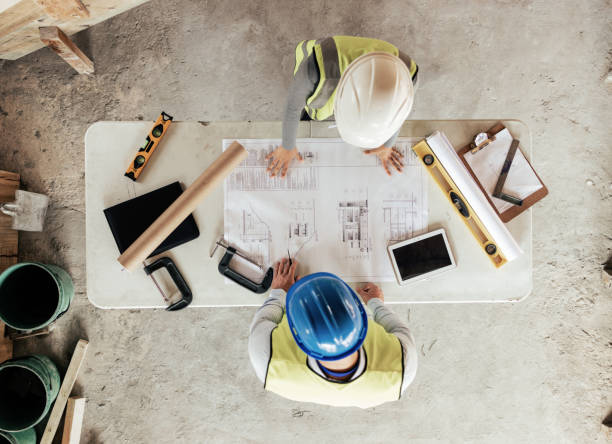 istock Architect, engineer and planning with blueprint, paper and collaboration for construction design for building. Floor plan, engineer or teamwork with architecture, creative idea or talking from above 1447581952