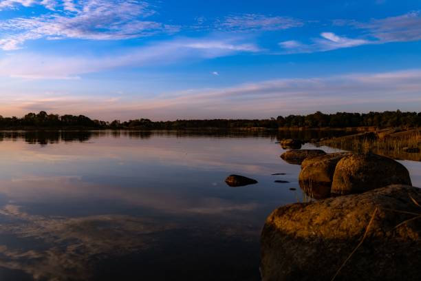 istock Reflection of clouds and twilight sky over the clear water surface surrounded by rocks 1447583218
