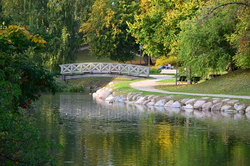 Beautiful scenery of a park with a bridge over a lake and green nature in autumn in Cesis, Latvia