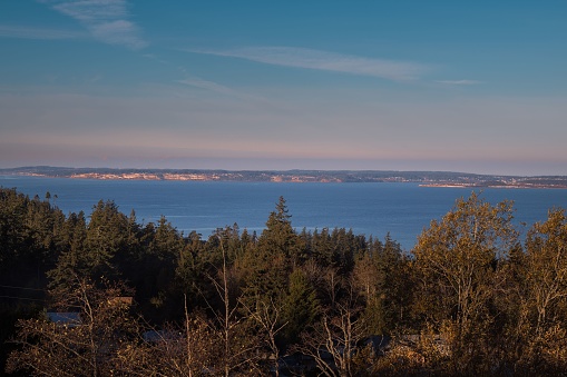VIEW OF WHIDBEY ISLAND FROM CAMANO ISLAND WITH A NICE SKY AND EVERGREEN TREES IN THE FOREGROUND