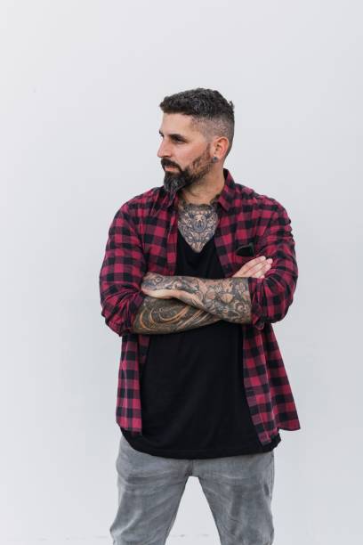 istock Handsome tattooed man posing on a white wall background with crossed arms 1447587380