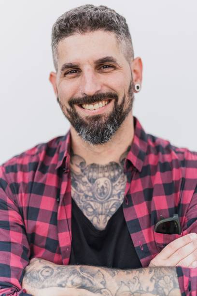 istock Handsome tattooed man posing on a white wall background with crossed arms 1447587387