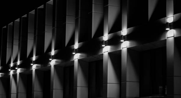 istock Grayscale exterior shot of modern facade with pattern poles wotj illuminated lights 1447591507