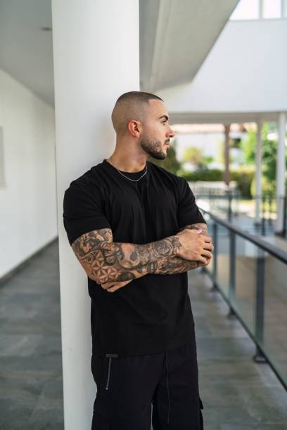 istock Cool Caucasian man with tattoos leaning on a post 1447593217