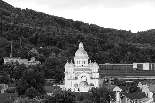A monochrome shot of an orthodox church with forest trees in the background