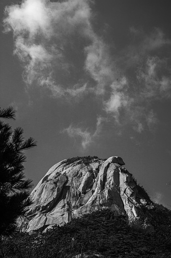 A grayscale view of inselberg against cloudy sky background
