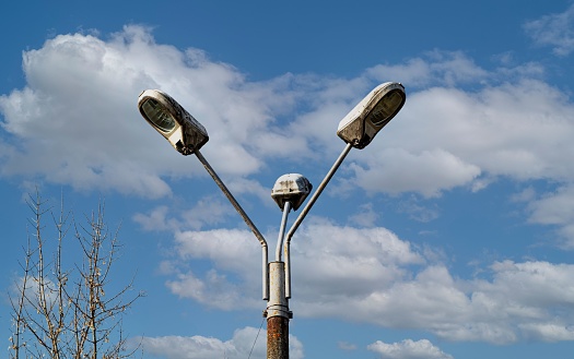 A triple street light pole against blue cloudy sky
