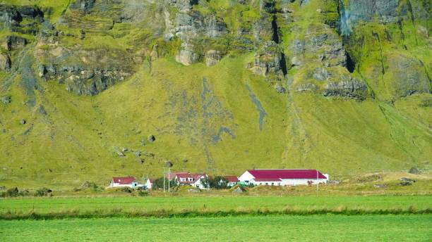 istock Low-angle of Skogafoss waterfall sunlit yellowing sky around lake reflecting it 1447595290