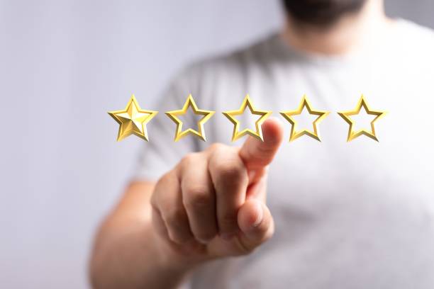 istock Man pointing to an illustrated five-star feedback with a blurry background 1447595690
