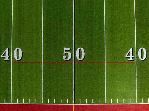 Example aerial image of a typical synthetic turf football field 50 yard line in white.