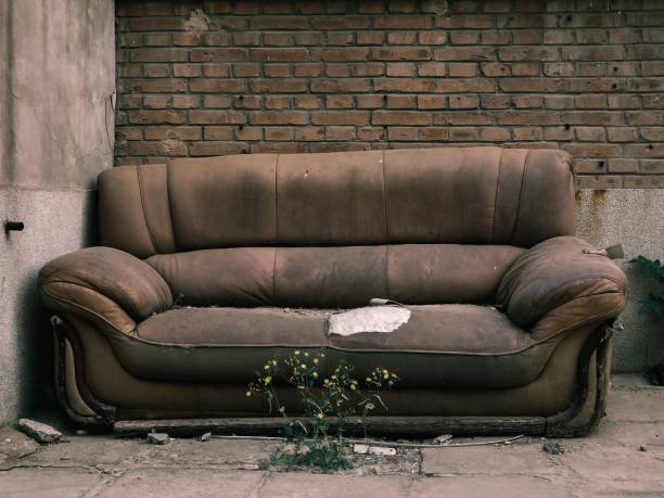 istock View of an old, damaged couch on the brick wall background 1447596487