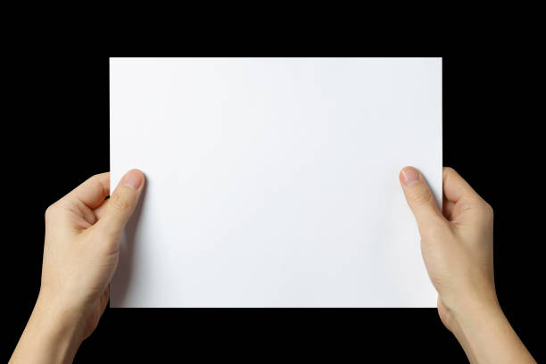 istock Hands holding a sheet of white paper on black 1447596990