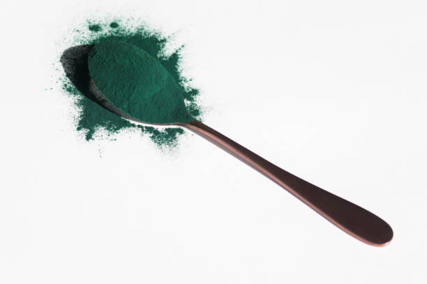 istock Spoon with spirulina powder on white background 1447601806