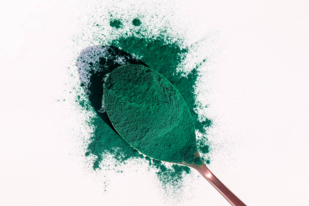 istock Spoon with spirulina powder on white background 1447601810