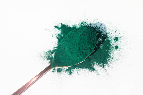 istock Spoon with spirulina powder on white background 1447601811