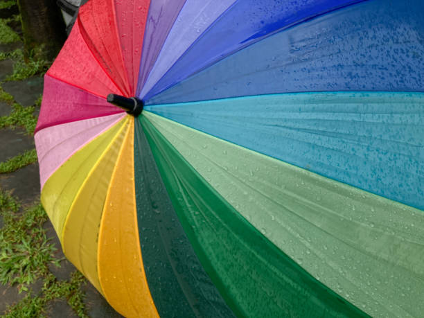 istock Rain drops falling onto umbella with rainbow colour. Rainy weather 1447604879