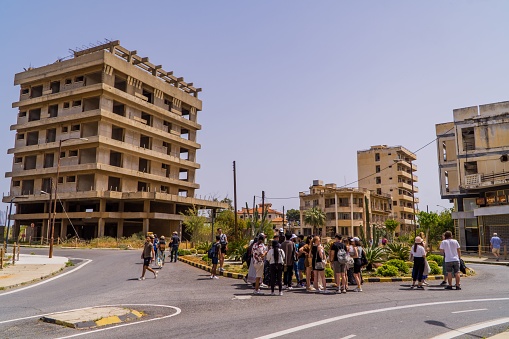 Varosha, Cyprus – April 26, 2022: A crowd of tourists around abandoned buildings in Varosha, Cyprus