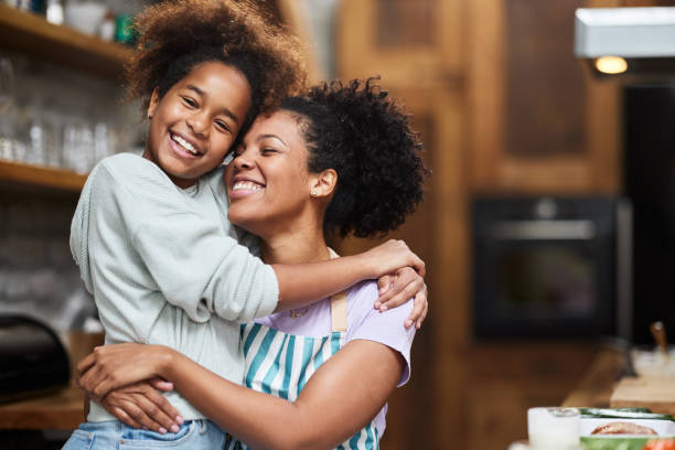 Happy single black mother and daughter embracing at home. stock photo