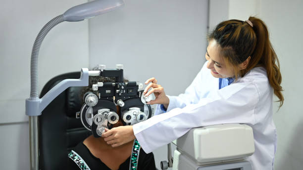 istock Image of child girl looking through optical phoropter during checking eyesight with optometrist. 1447609786