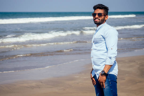 young african american man in blue shirt and jeans on the ocean beach. - party beach indian ethnicity adult imagens e fotografias de stock