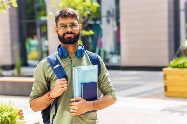 istock indian student with blue headset and backpack holding books at sunny day 1447616536
