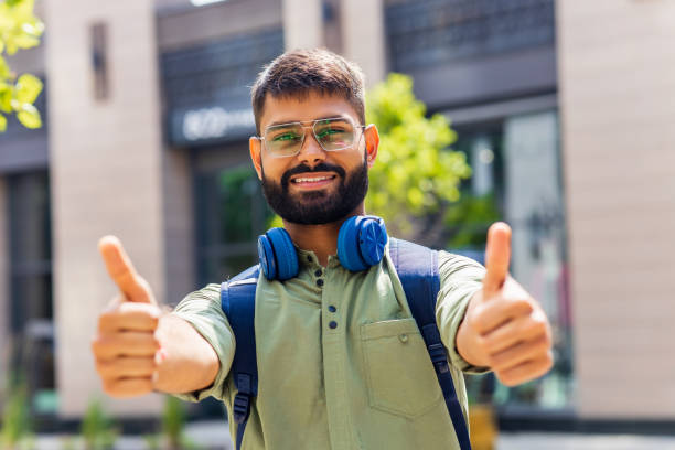 istock student looking happy and showing friendly gesture outdoors 1447616544