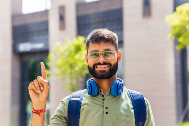 istock student looking happy and showing friendly gesture outdoors 1447616548