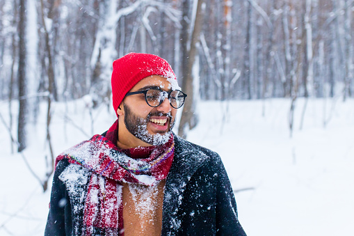 portrain of indian man in red hat with throwing snow on his face.