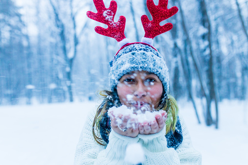 Happy indian woman having fun and enjoying first snow wear fun hat deer horn.