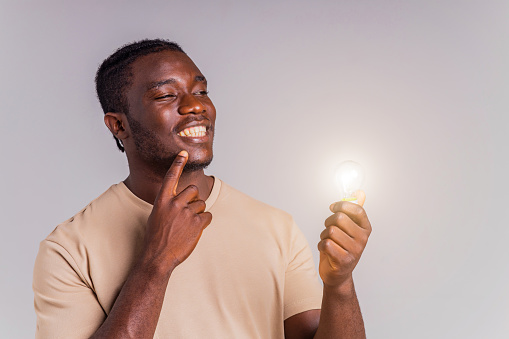 latin brazilian man holding a lightbulb in hands concept of idea and creativity.