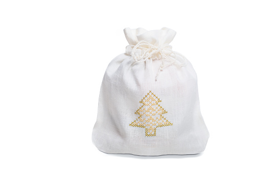 Isolated linen gift sack decorated with embroidered Christmas tree on white background, holiday concept, copy space