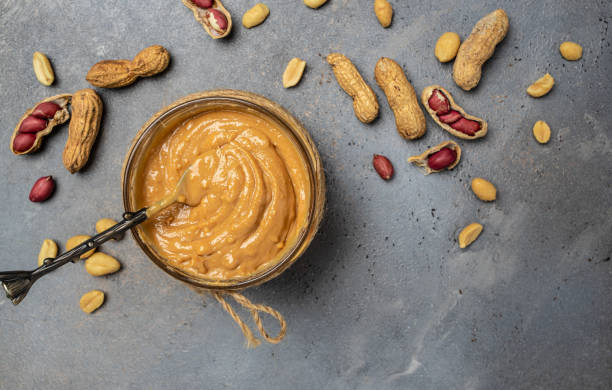 istock peanut paste in an open jar in spoon near creamy peanut butter peanuts scattered on a dark background, place for text, top view 1447620079