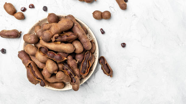 istock Delicious ripe tamarinds on a wtite plate on a light background, Long banner format. top view 1447620295