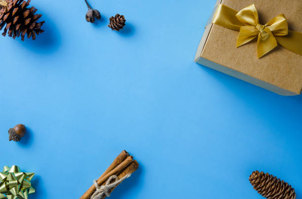 istock Christmas frame with gift box, conifer cones, cinnamon and ornaments on blue paper background with copy space 1447620864