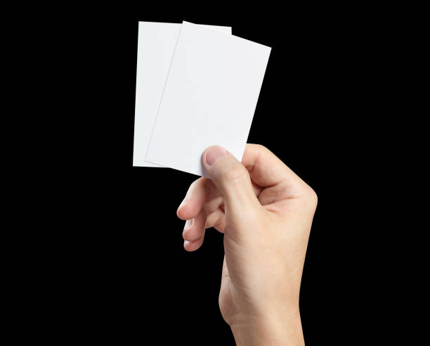 istock Hand holding two small pieces of paper or plastic on black 1447626603