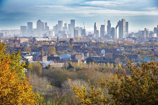 View across London towards the high rise skyscrapers and financial district as seen from the leafy green vantage point of Hampstead Heath.