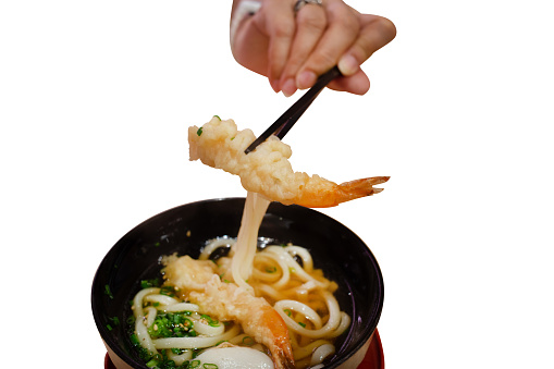 Die cut of hand with chopsticks Delicious Japanese Udon ramen with shrimp tempura in bowl on white isolated.