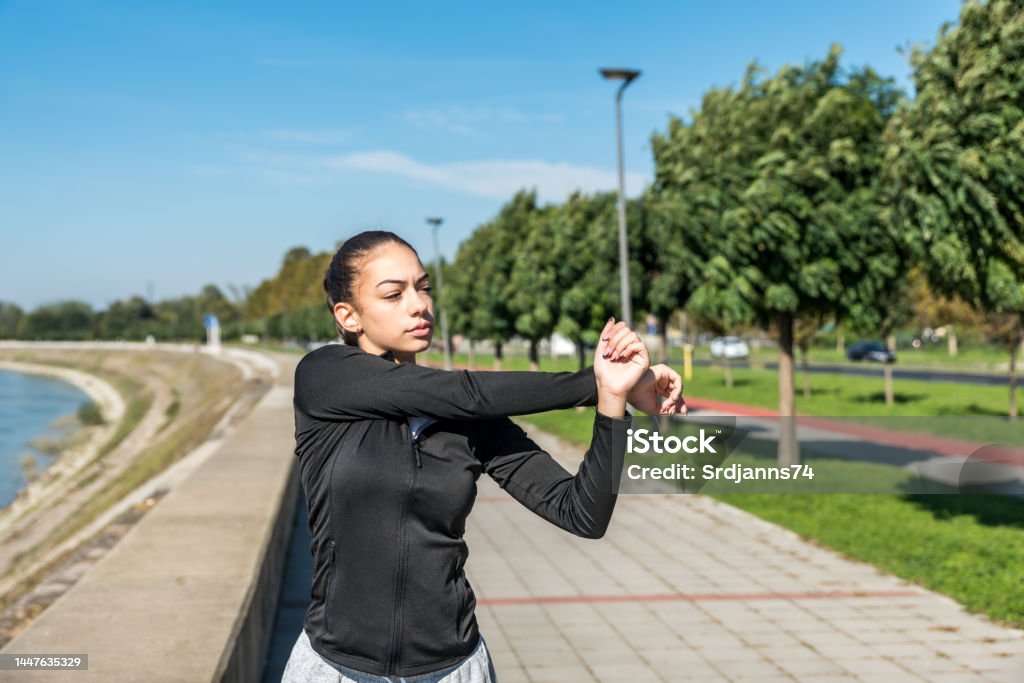 Young self loved teenage girl fitness exercises outdoor as morning routine for self-awareness of healthy life. Good posture woman stretching her muscles before workout training. Active Lifestyle Stock Photo