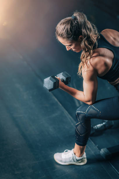 Female Athlete Exercising with Dumbbells in the Gym. stock photo