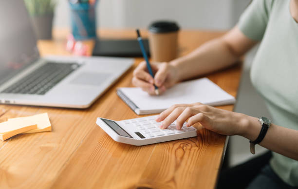 istock Closeup image of a woman writing and taking note on notebook with calculator in office. 1447641239