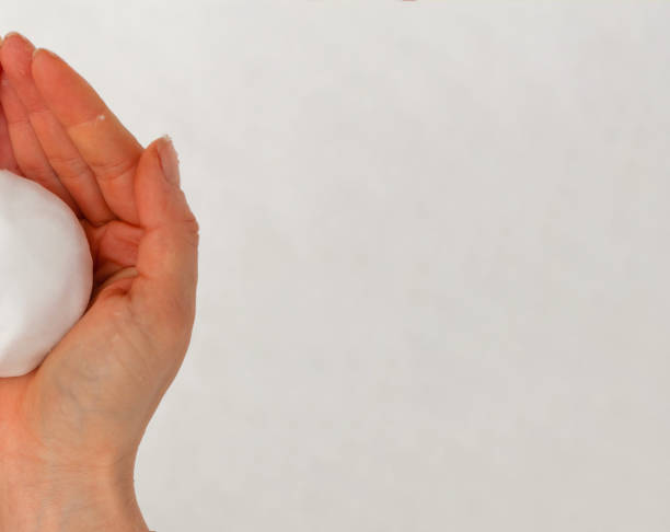 istock One human hand without gloves and half a snowball 1447647282