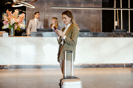 Confident businesswoman on mobile phone in the hotel lobby. She's on a business trip. Travel, symposium