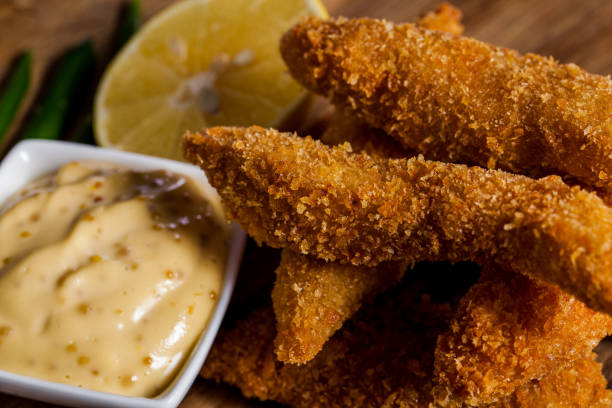 istock Breaded sea fish with sauce, lemon on a wooden table. Horizontal orientation 1447652038